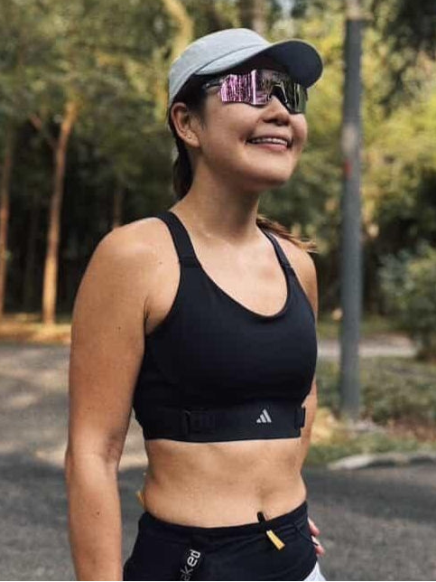 Woman outdoors wearing polarized UV protection sunglasses, sports bra, and cap